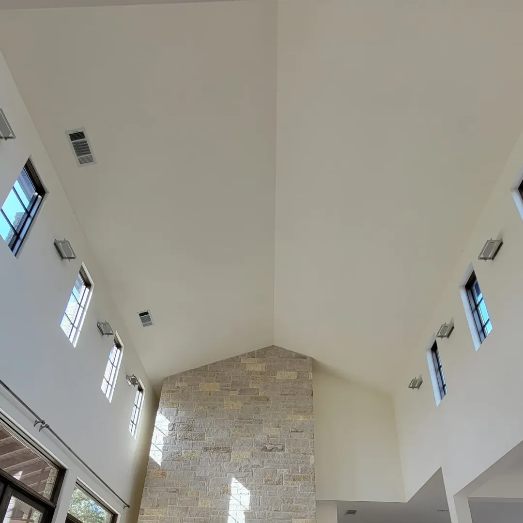 Tall white vaulted room and stone fireplace before the custom wood ceiling installation.