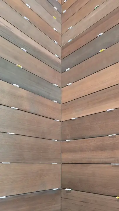 Horizontal wood cladding installation with spacers maintaining consistent reveals at an inside corner.