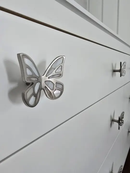 Butterfly-shaped hardware installed on painted casework drawers at Stoneridge.