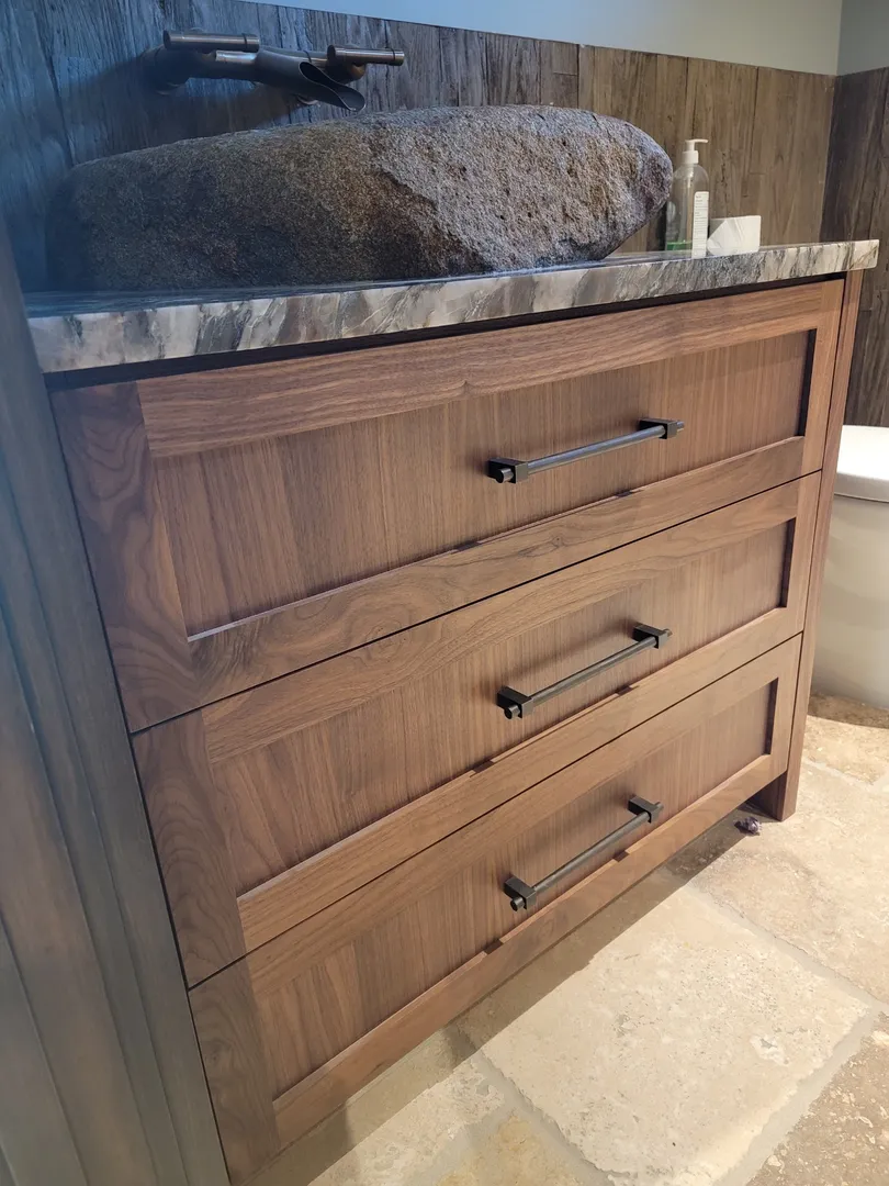 Custom wood vanity with integrated drawers, stone basin, and precise hardware alignment.