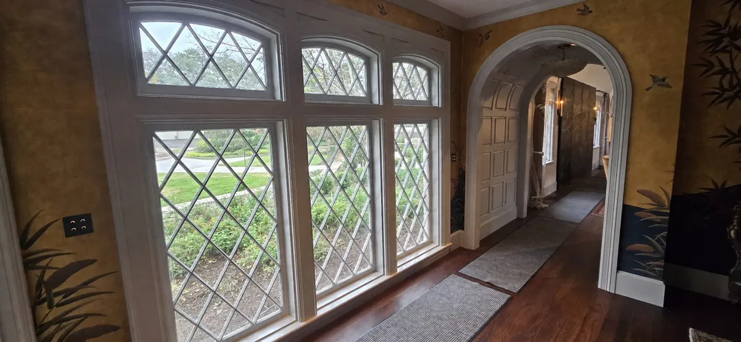 Finished corridor with diamond-pane windows and an arched paneled passage.
