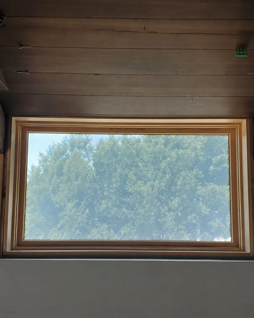 Custom wood window surround aligned with adjacent paneled wall and ceiling surfaces.